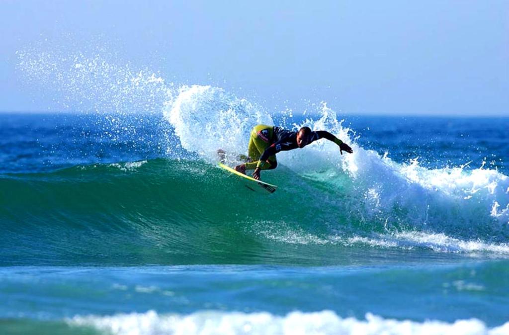 um homem a surfar uma onda numa prancha de surf no oceano em Brisa de Mar apartamento Costa da Caparica em Costa da Caparica
