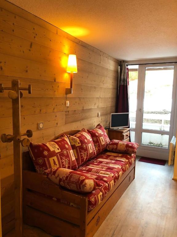 - un canapé dans une chambre dotée d'un mur en bois dans l'établissement Résidence Les Horizons d'Huez - maeva Home - Appartement 2 pièces 4 personnes Sélection MAE-3559, à Huez