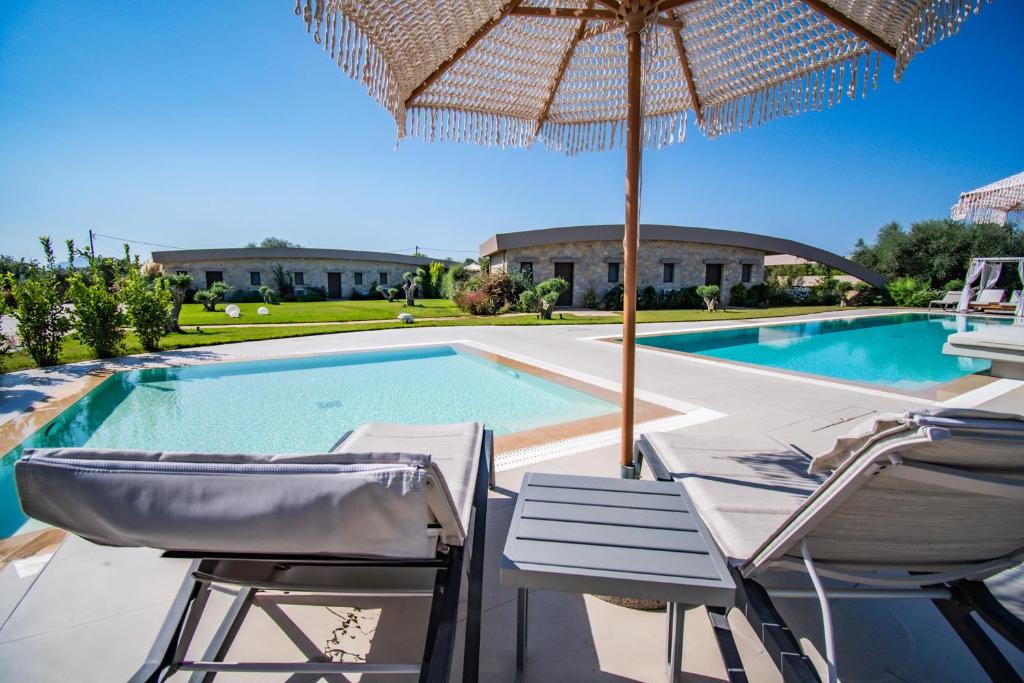 a swimming pool with two chairs and an umbrella at Nestor Luxury Villas in Romanu