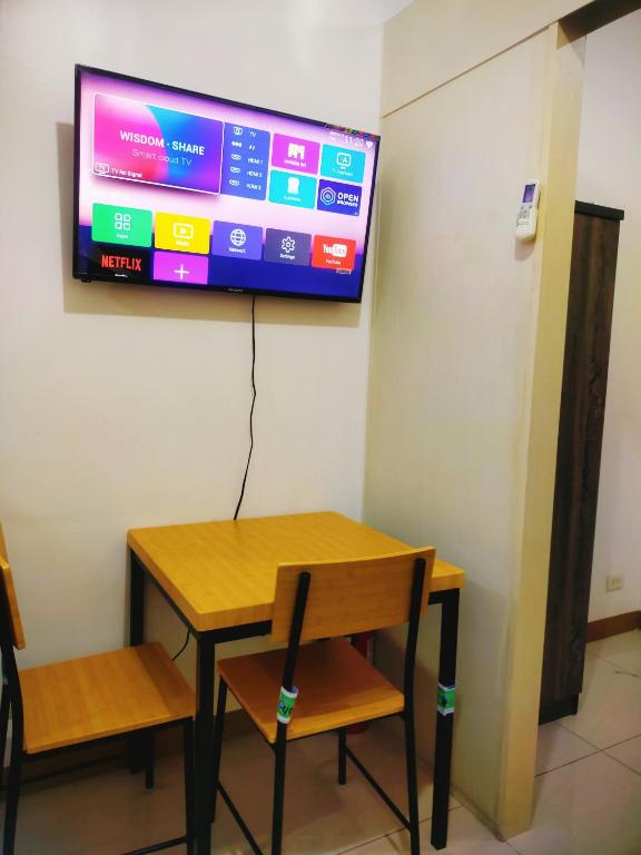 a table and two chairs and a television on a wall at 1br condo 25mins to NAIA SMDC South - 323T2 in Manila