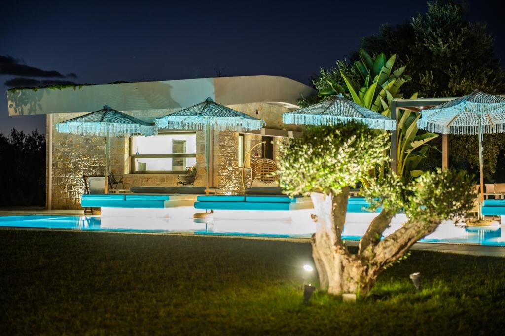 a villa with a swimming pool at night at Nestor Luxury Villas in Romanu