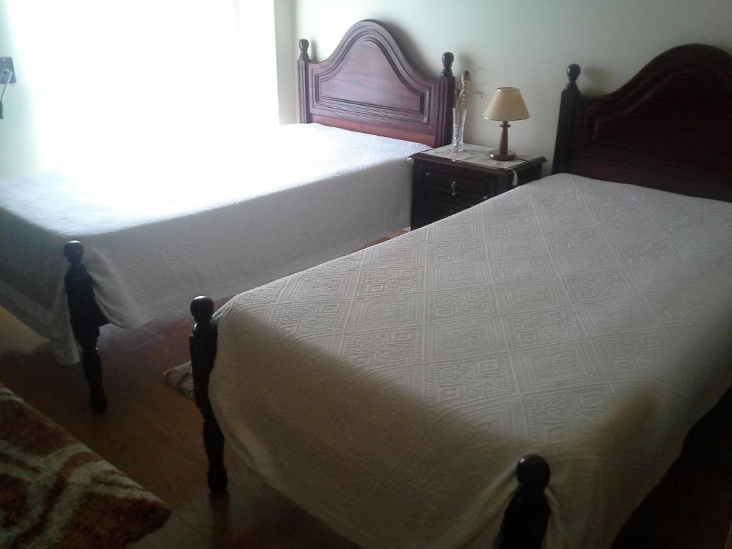 a bedroom with two beds and a lamp on a table at Borges Pimentel Apartment in Ponta Delgada