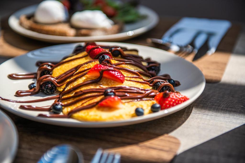 a plate of pancakes with fruit on a table at Nestor Luxury Villas in Romanu