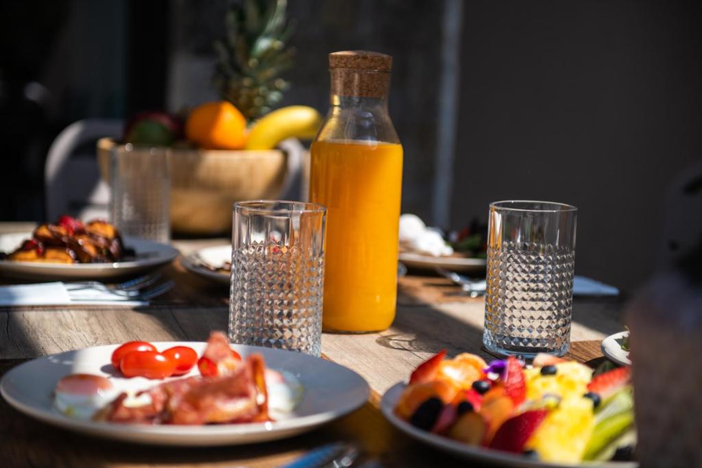 a table with plates of food and a bottle of orange juice at Nestor Luxury Villas in Romanu