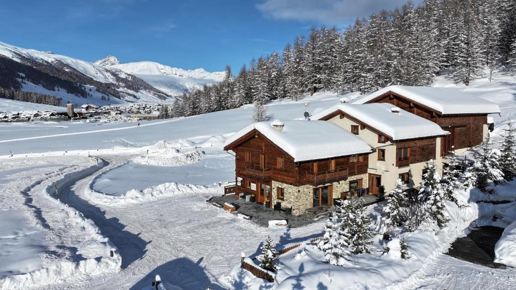 una cabaña en la nieve con una montaña cubierta de nieve en Agriturismo Bosco d'oro Livigno, en Livigno