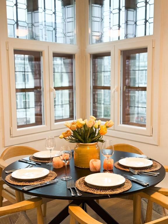 a dining room table with chairs and a vase of flowers at Le FauBourg Suites in Antwerp