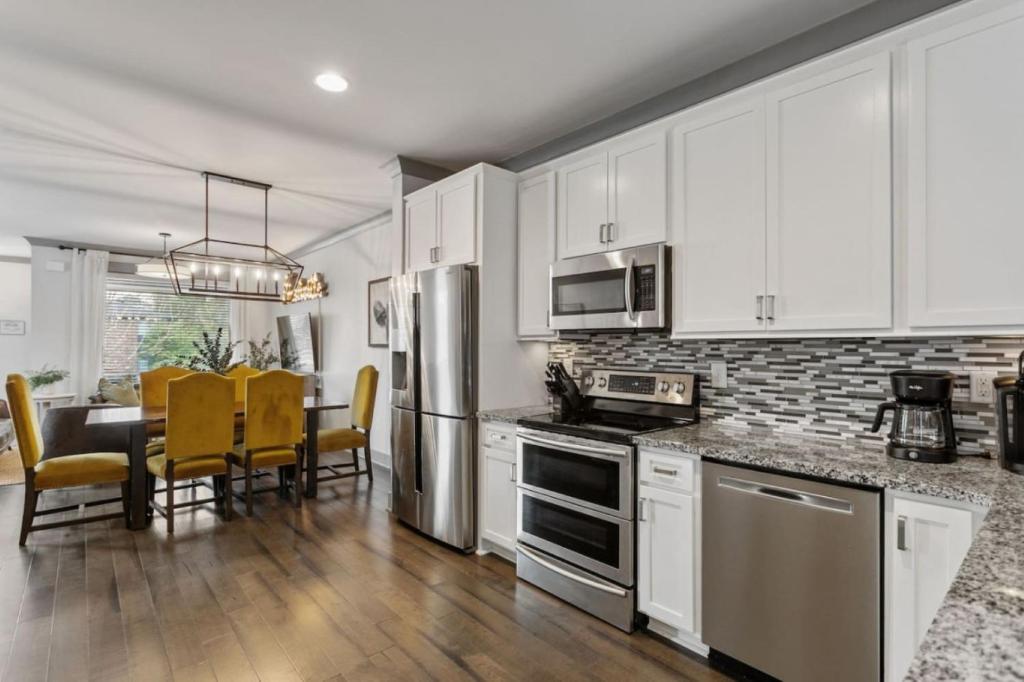 ナッシュビルにあるLuxury 4 Bedroom Home, Heart of the Entertainmentのキッチン(白いキャビネット、テーブル、黄色い椅子付)