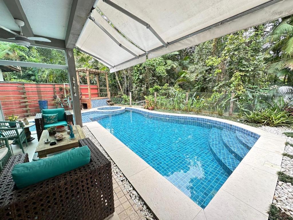 ein Bild eines Swimmingpools mit einem Sonnenschirm in der Unterkunft Guaratuba 2 sobrado cinematográfico próximo da praia in Bertioga
