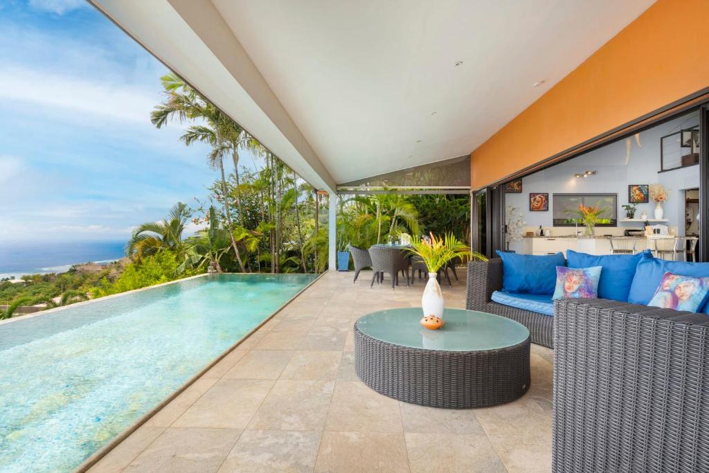 a swimming pool in a house with a couch and a table at Villa Ireina magnificent sea view in Punaauia