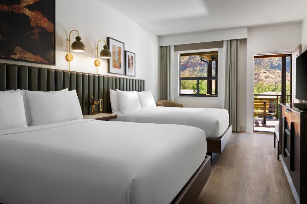 a hotel room with two beds and a television at The Red Cliffs Lodge Zion, a Tribute Portfolio Hotel in Springdale