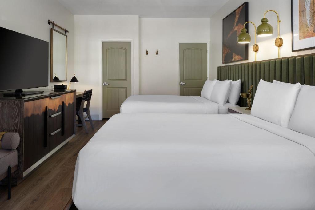 a hotel room with two beds and a flat screen tv at The Red Cliffs Lodge Zion, a Tribute Portfolio Hotel in Springdale
