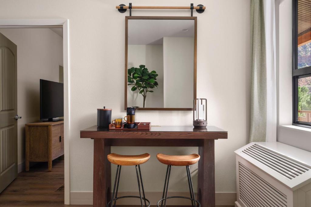 a dressing table with two stools and a mirror at The Red Cliffs Lodge Zion, a Tribute Portfolio Hotel in Springdale