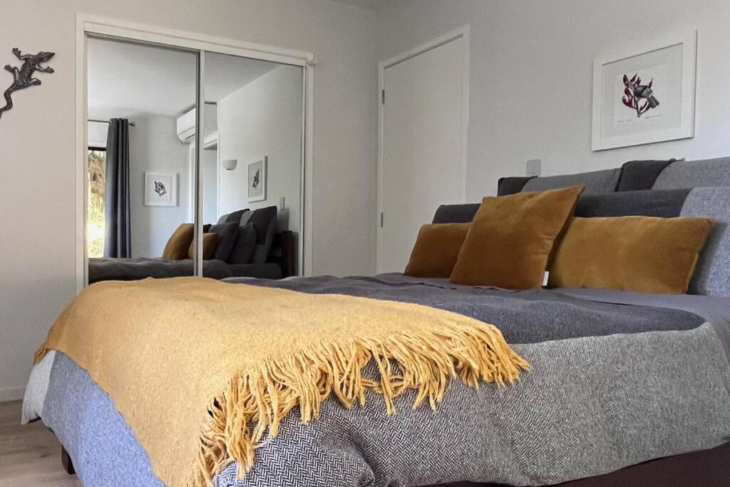 a bedroom with a bed with a yellow blanket on it at The Aotearoa Room in Auckland