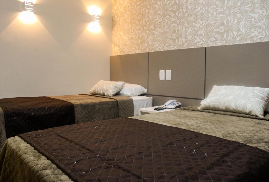 Habitación de hotel con 2 camas y teléfono en Hotel Caju de Ouro en Feira de Santana