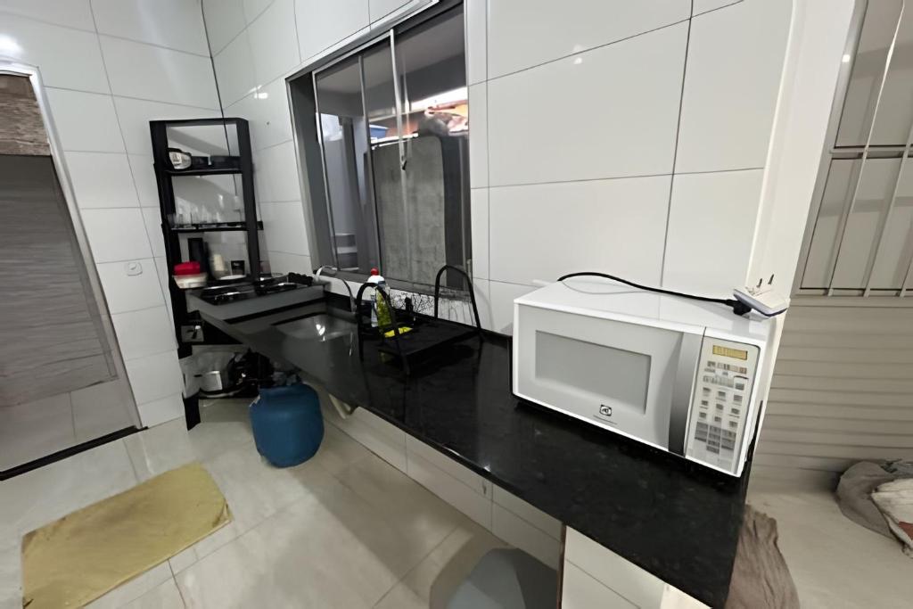 eine Küche mit einer Mikrowelle auf einer schwarzen Theke in der Unterkunft Bela casa 3 quartos perto do Buritis in Belo Horizonte