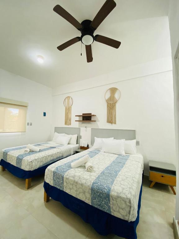 two beds in a bedroom with a ceiling fan at Casa Coronaa Holbox México in Holbox Island