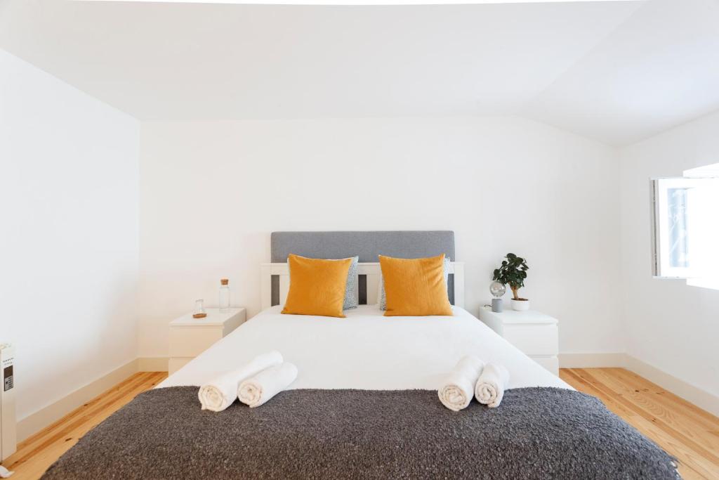 a bedroom with a large white bed with orange pillows at Suite in Cozy Apartment in Chiado in Shared House in Lisbon