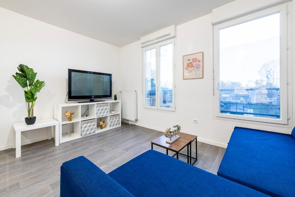 a living room with a blue couch and a tv at Studio Cosy proche Paris - Aeroport CDG - Le Bourget - T11 - Parc des expositions in Drancy