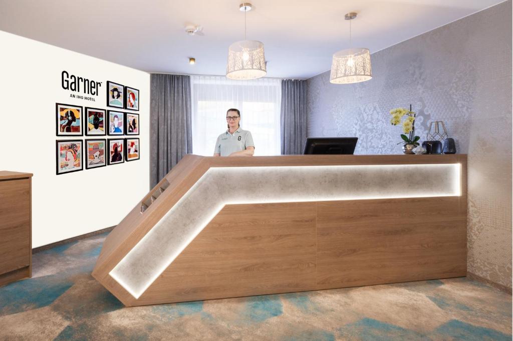 a man standing behind a reception desk in a room at Garner Hotel Hamburg Nord by IHG in Hamburg