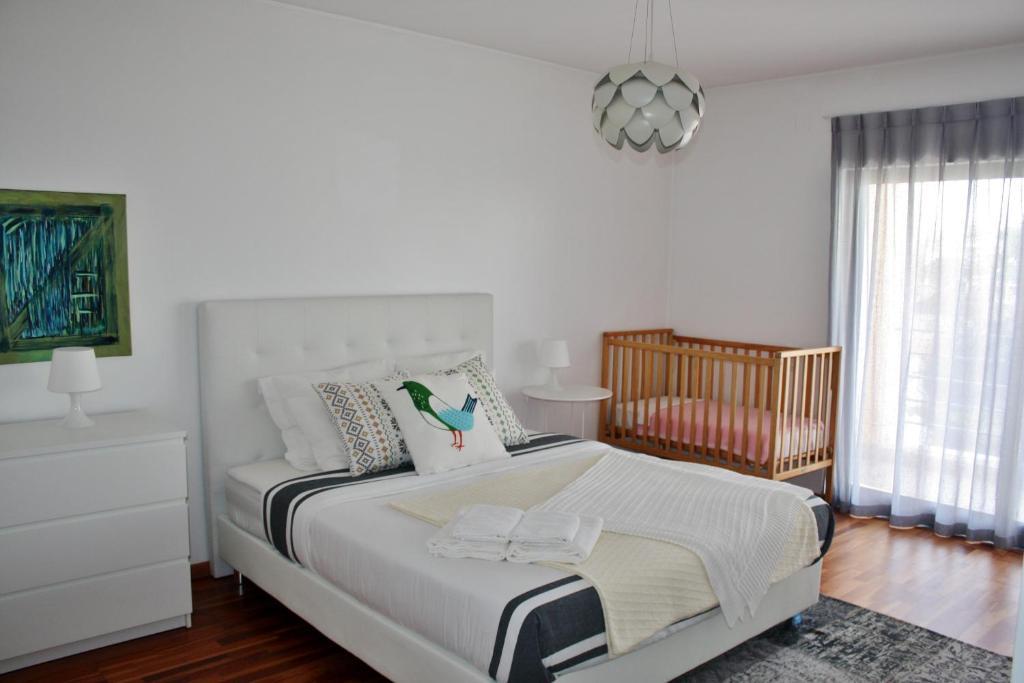 a white bedroom with a bed and a crib at Charming Cascais Apt. in Cascais