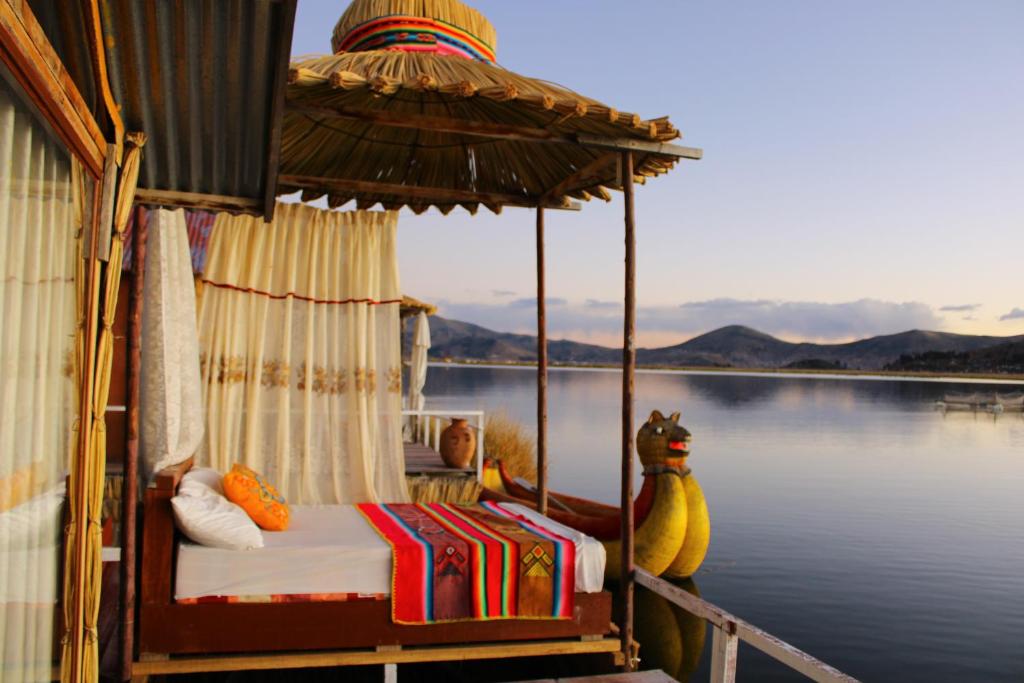 a boat with a bed and an umbrella on a body of water at TITICACA ISLAND LODGe in Puno