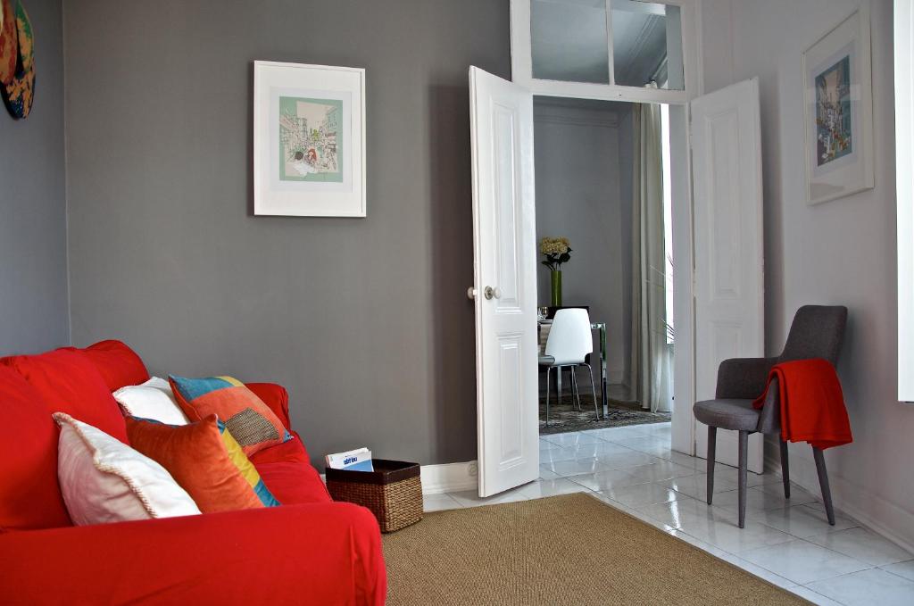 ein Wohnzimmer mit einem roten Sofa und einem Stuhl in der Unterkunft Chiado Lisbon Apartment in Lissabon