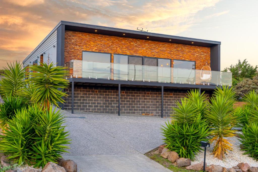 a brick house with a balcony on top of it at Hobart Luxury Family Home with Spa & Fire Pit, Sleeps 8 in Sorell