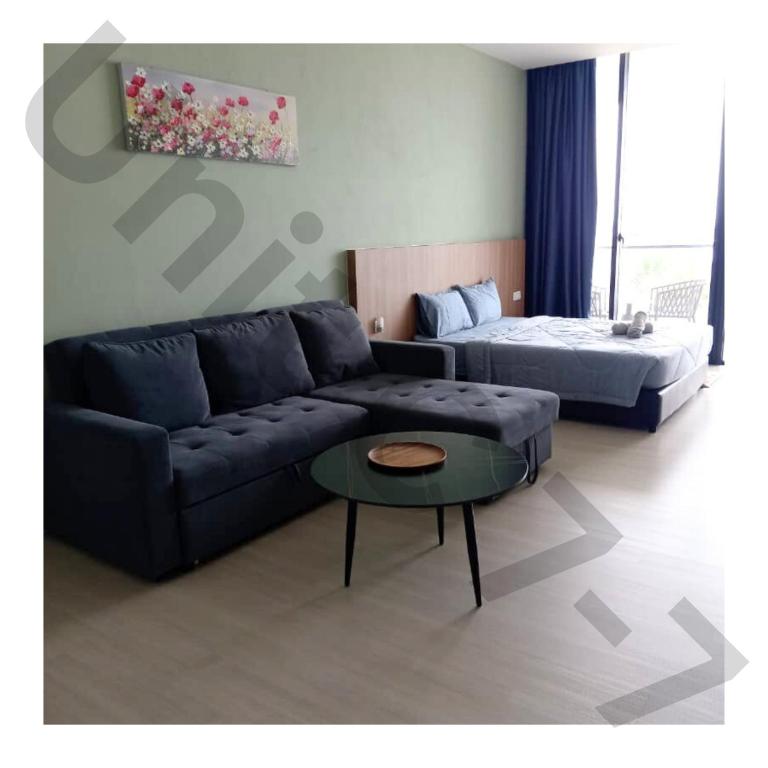 a living room with a couch and a bed at 7th Horizon - Roxy Sematan Beach Apartment in Sematan