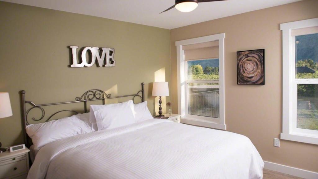 ein Schlafzimmer mit einem weißen Bett und einem Liebesschild an der Wand in der Unterkunft Klippers Guest Suites in Cawston