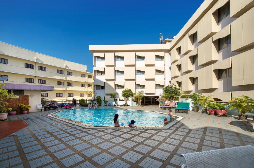 A rectangular outdoor pool sits in a paved courtyard between hotel buildings.