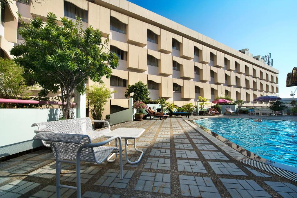 A sunlit pool deck beside the hotel’s multi-storey building.