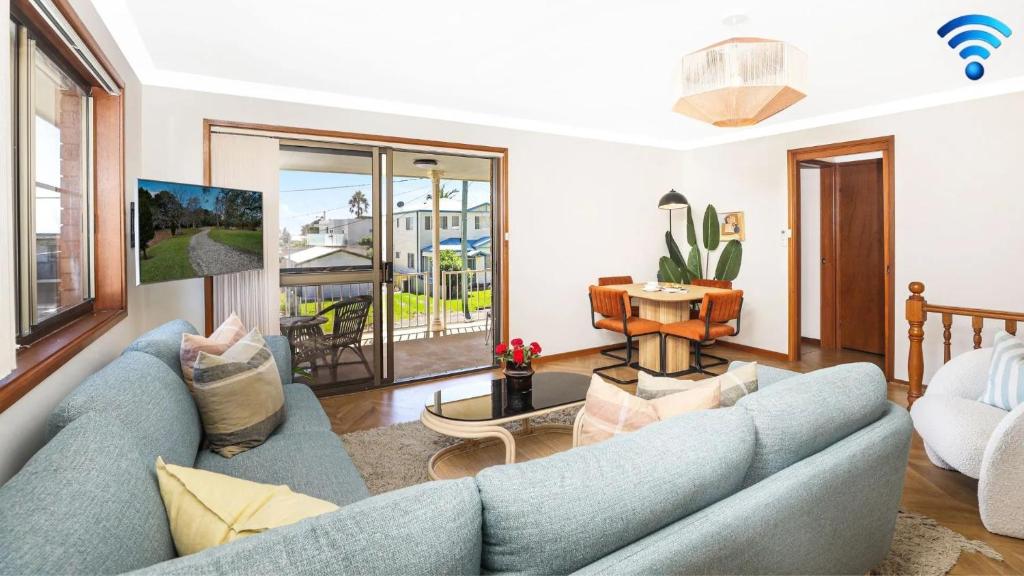 sala de estar con sofá azul y piano en Sylvia's at Currarong, en Currarong