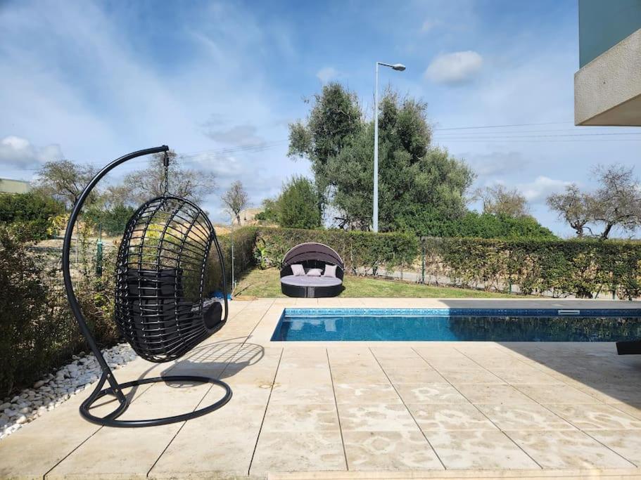 a bird cage sitting next to a swimming pool at Casa Rogel by Armação de Pêra with Heated Pool and Games Room in Alcantarilha