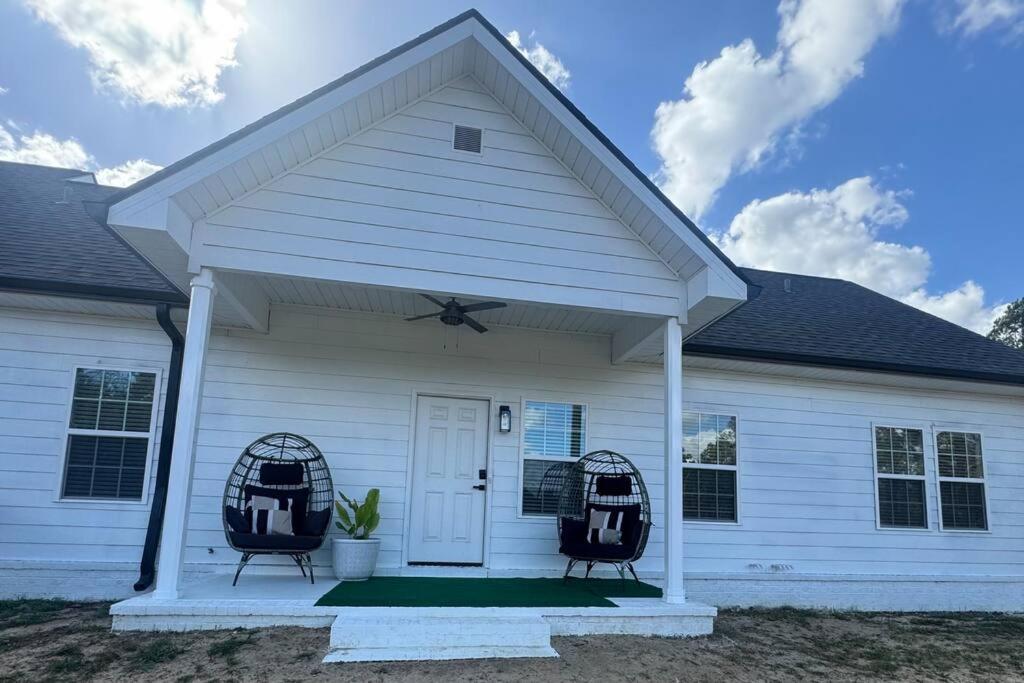 a white house with two chairs on the porch at A Charming Villa in Vidalia GA - New Construction in Vidalia