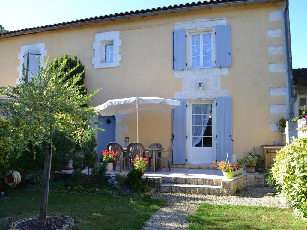 dom z niebieskimi okiennicami oraz stołem i krzesłami w obiekcie Gîte familial avec jardin au bord de l'eau, terrasses, vélo, jeux, proche Charente, WiFi inclus - FR-1-653-189 w mieście Saint-Genis-dʼHiersac