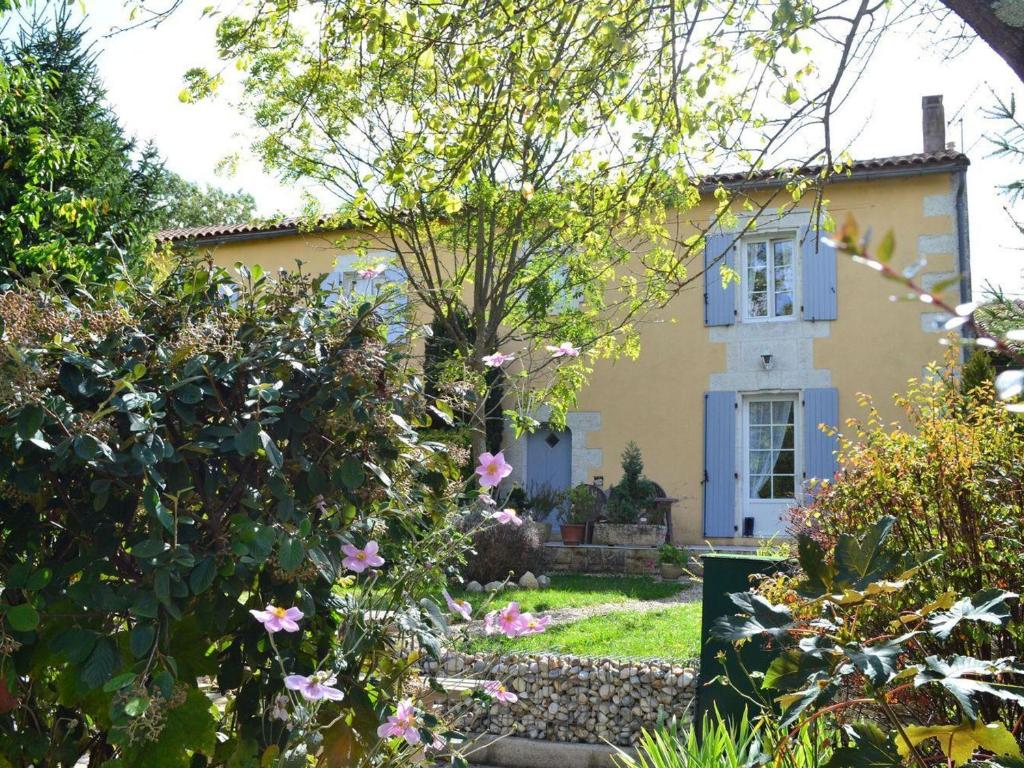 żółty dom z niebieskim oknem i kilkoma kwiatami w obiekcie Gîte familial avec jardin au bord de l'eau, terrasses, vélo, jeux, proche Charente, WiFi inclus - FR-1-653-189 w mieście Saint-Genis-dʼHiersac