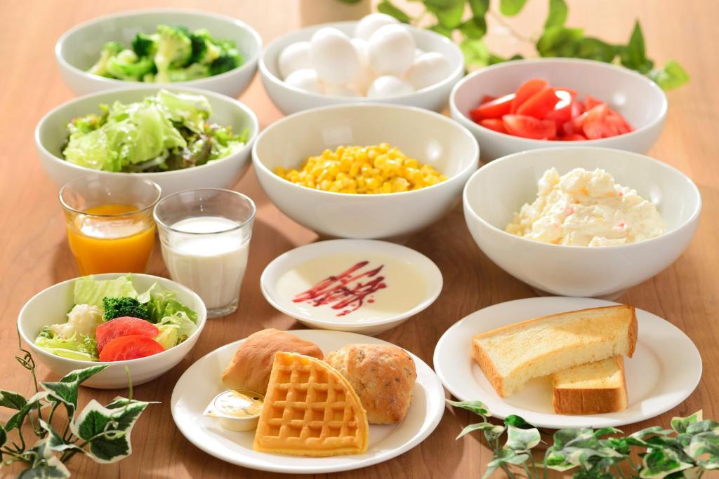 a table with plates of food and bowls of food at Kanazawa Manten Hotel Ekimae in Kanazawa