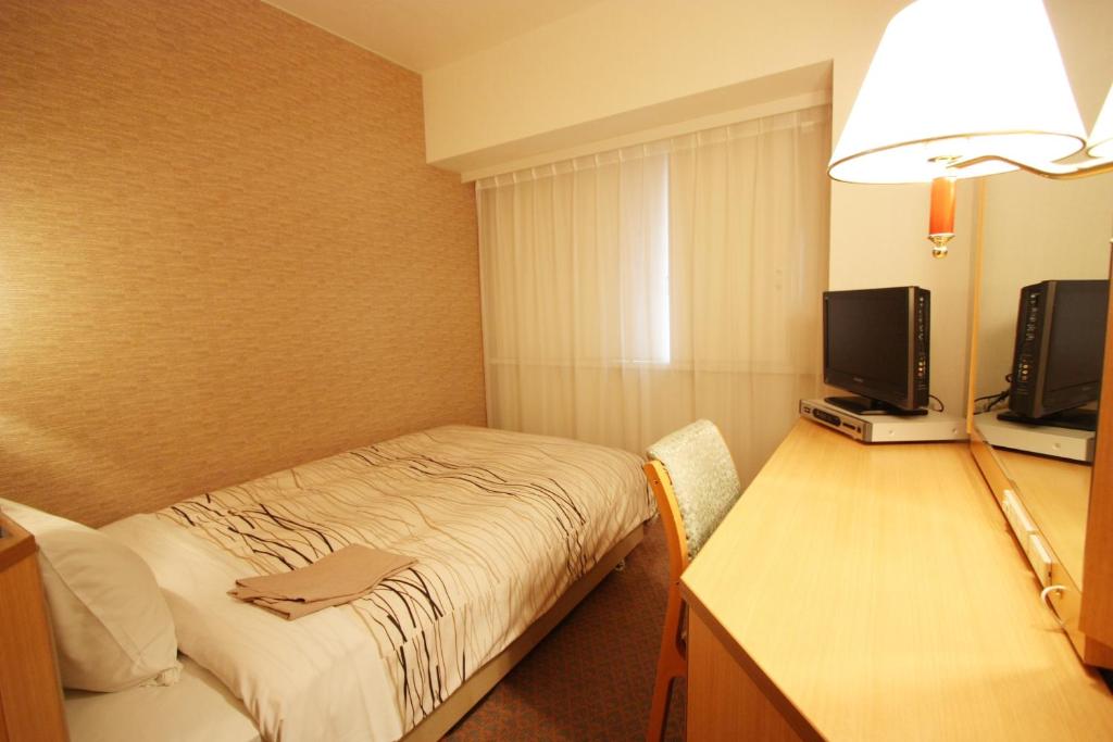 a small room with a bed and a television at Kanazawa Manten Hotel Ekimae in Kanazawa