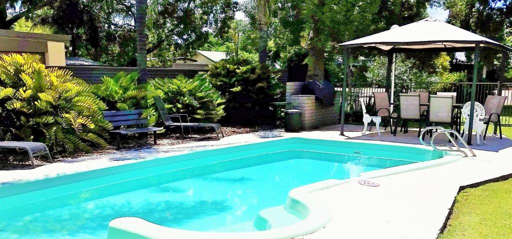 una piscina en un patio con sombrilla en Biloela Countryman Motel, en Biloela