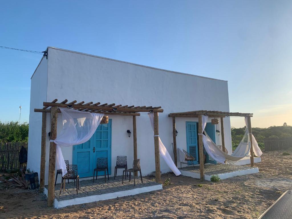 ein weißes Gebäude mit Stühlen und Hängematten davor in der Unterkunft Cajumar in Cajueiro