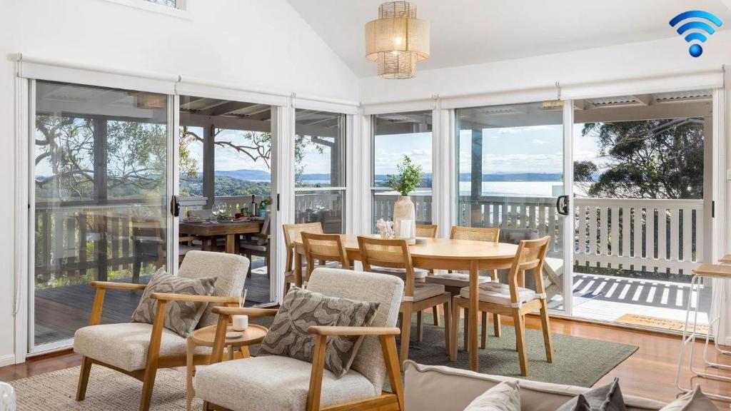 Un comedor con mesa y sillas y ventanas. en Cabane Sur Mer, en Shoal Bay