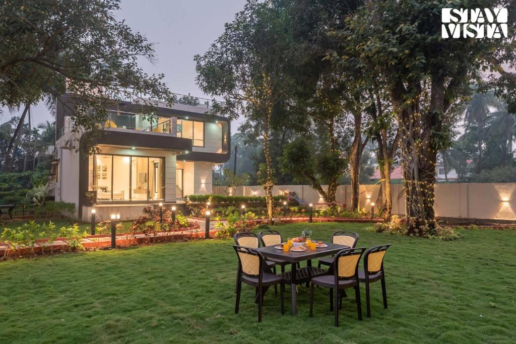 a table and chairs in front of a house at Cashew Creek by VEO - Part of StayVista with Pool & WiFi in Alibaug