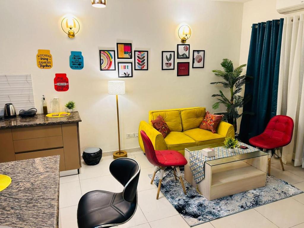 sala de estar con sofá amarillo y sillas rojas en Maize - Aashray, en Noida