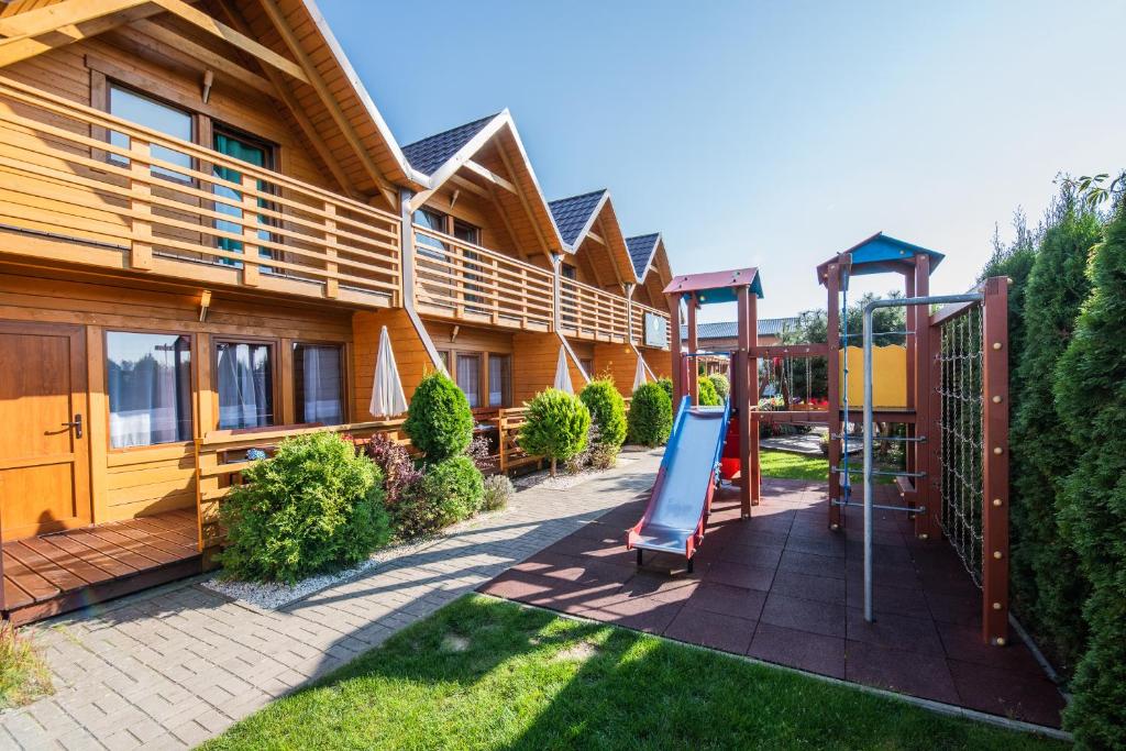 a playground in front of a house with a slide at Sunrise-Sarbinowo domki i apartamenty in Sarbinowo