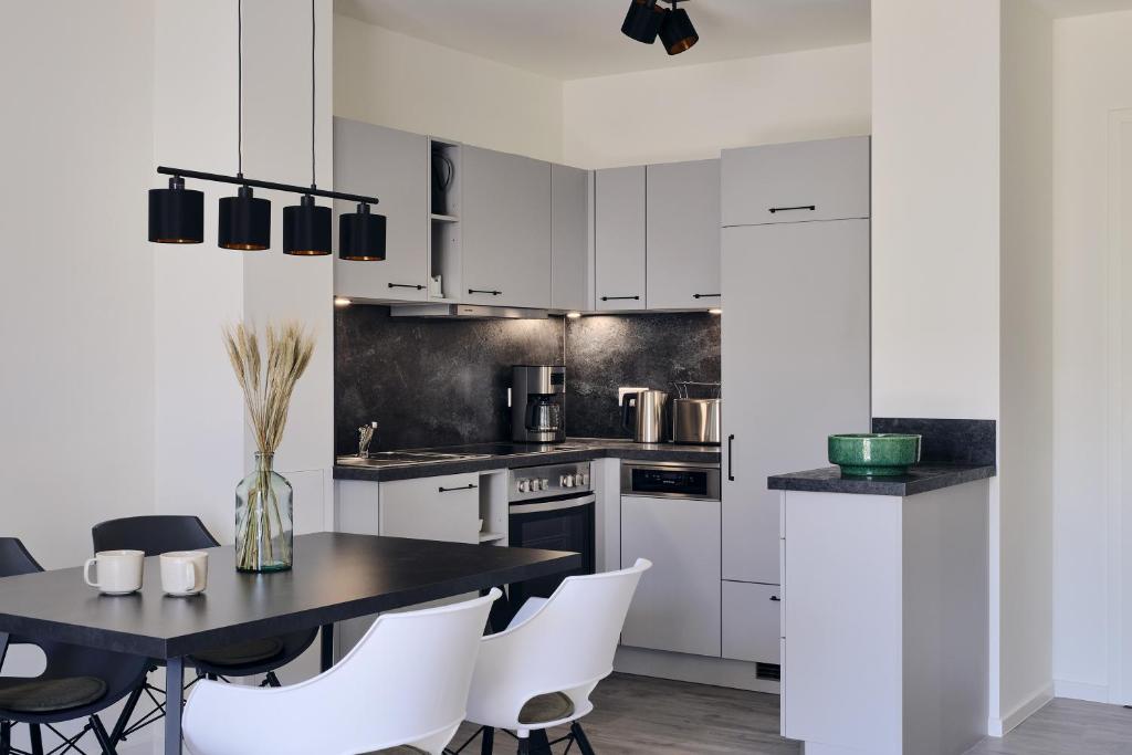 a kitchen with white cabinets and a black table and chairs at Apartment B 2 "Pine Hill Resort" Allergikerfreundlich & Extra Bike Friendly in Zirchow