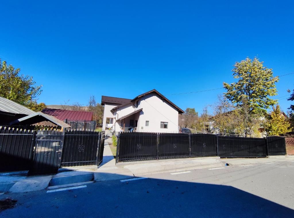 ein schwarzer Zaun vor einem weißen Haus in der Unterkunft Casa Noastra in Drajna de Sus