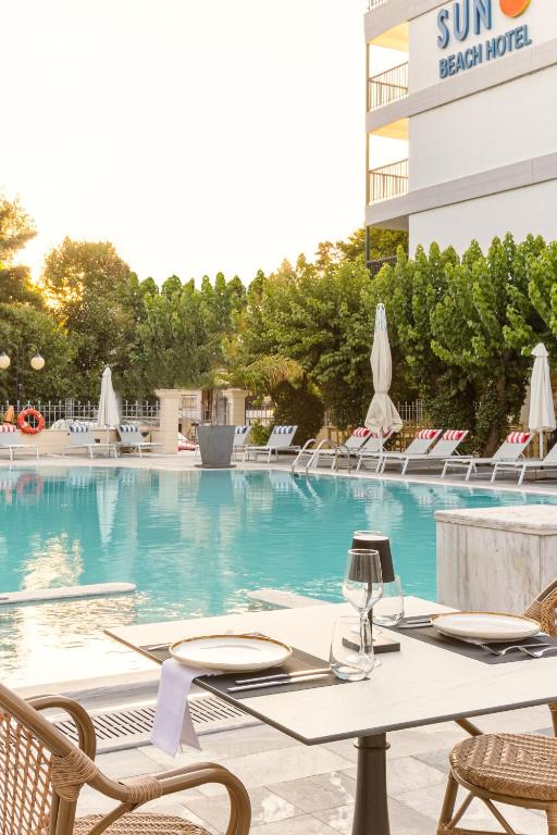 a table and chairs in front of a swimming pool at Sun Beach Hotel in Agia Triada