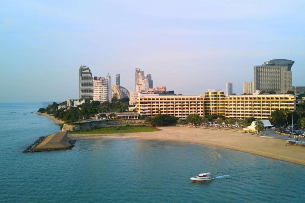 a boat in the water near a beach with buildings at Dusit Thani Pattaya in North Pattaya