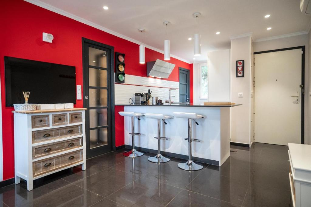 une cuisine aux murs rouges et un bar avec tabourets dans l'établissement GuestReady - Lovely Escape Caucade, à Nice