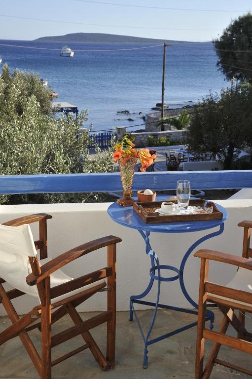 a table with a vase of flowers and two chairs at George's beach studios Aliki Paros in Aliki